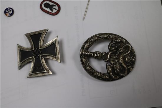 A German Iron Cross 1st class, an SS lapel badge number 792, dagger lapel pin, German army belt buckle, three German badges without pin